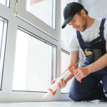 Construction worker installing window in house